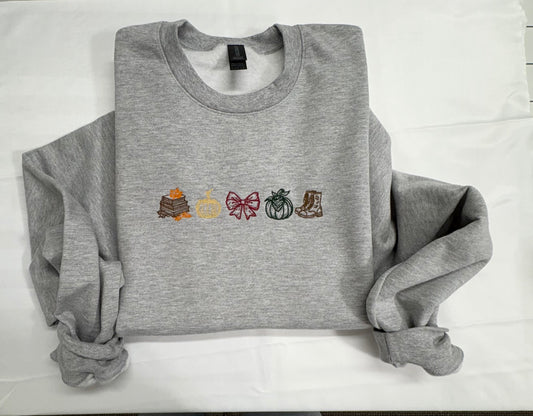 Heather gray crewneck sweatshirt embroidered with books and autumn leaves, two pumpkins, a burgundy bow, and boots