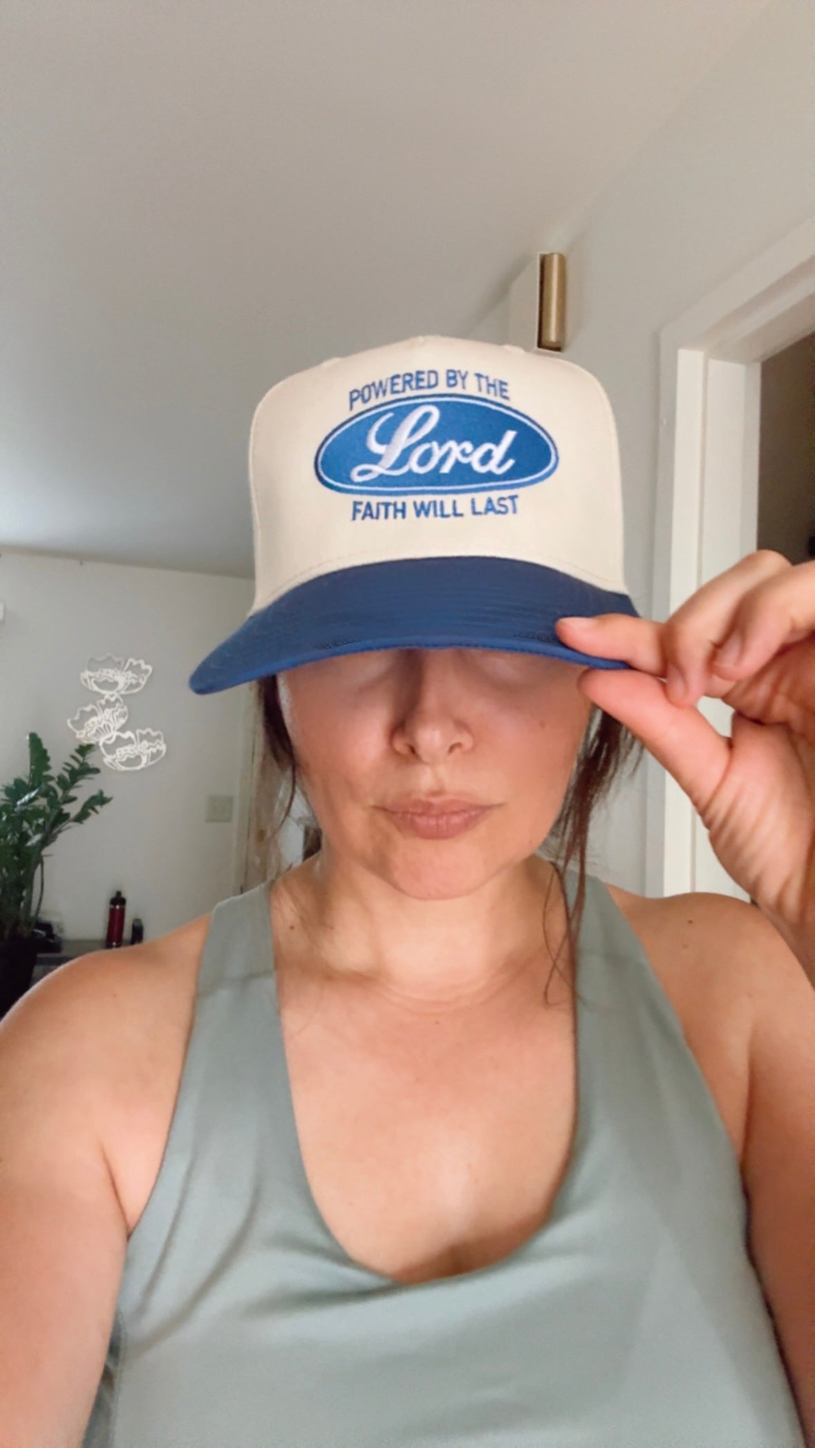Cream and blue hat worn by a woman, with Powered by the Lord and Faith Will Last design on the front